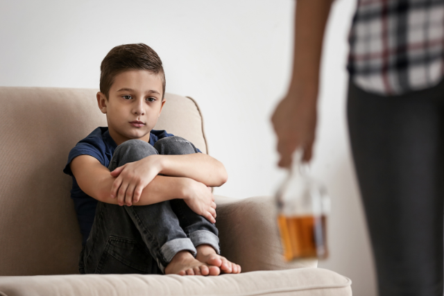 kid looking at parent holding bottle of alcohol